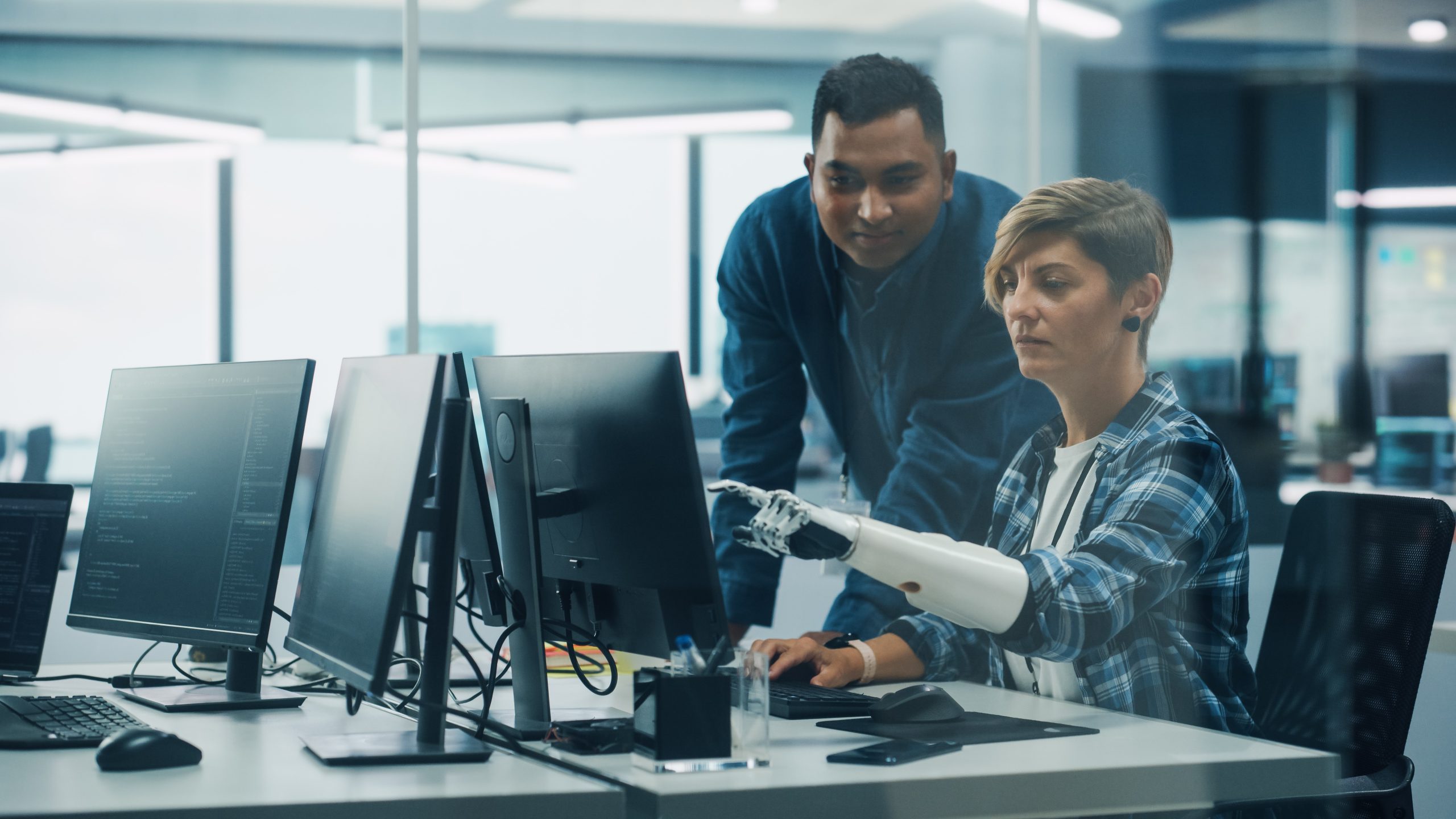 A woman and a man in an office setting looking at a computer monitor